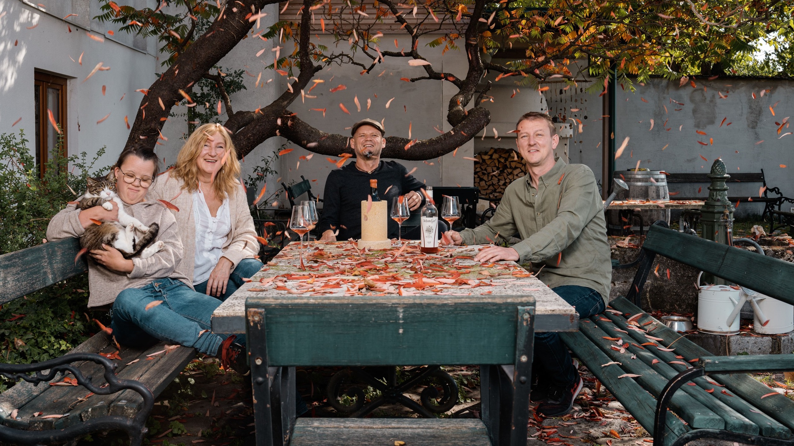 Die Familie Schmelzer sitzt auf einem Tisch im Garten des Weinguts